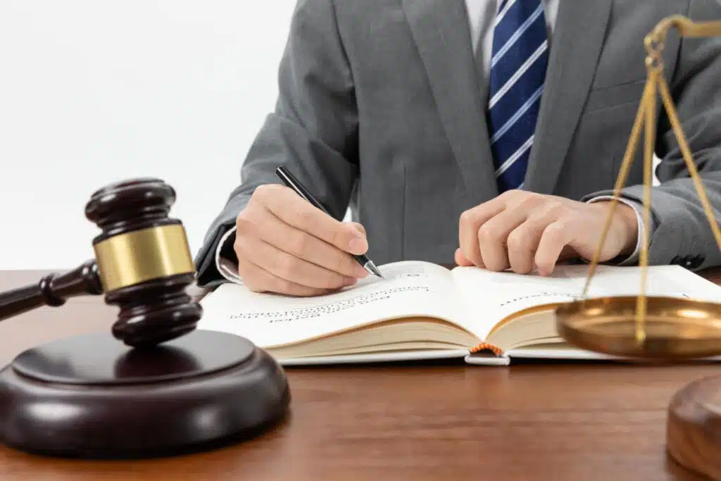 Lawyer writing in legal book with gavel and scales